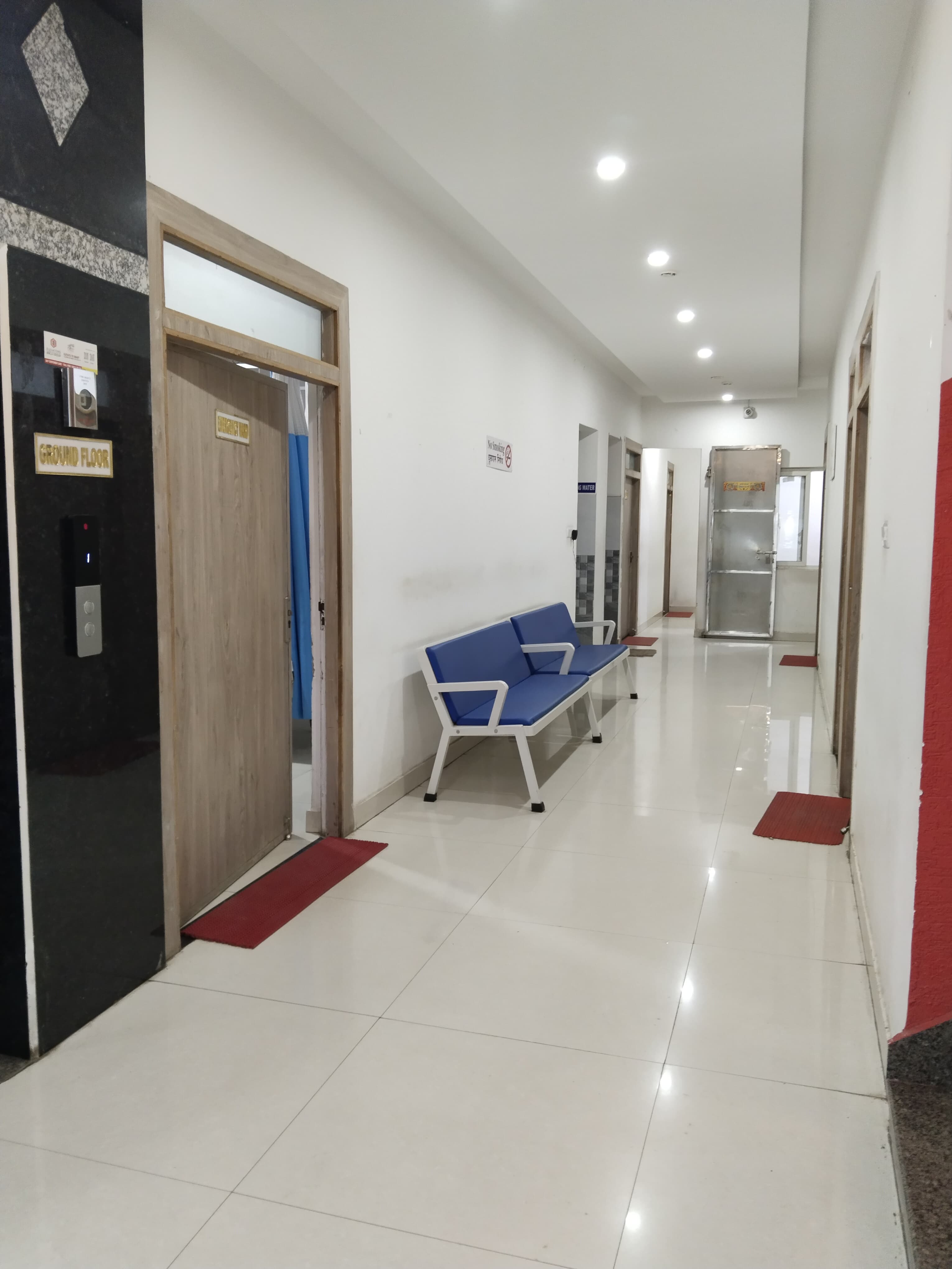 Clean hospital corridor with elevator access, seating area, and well-lit passages