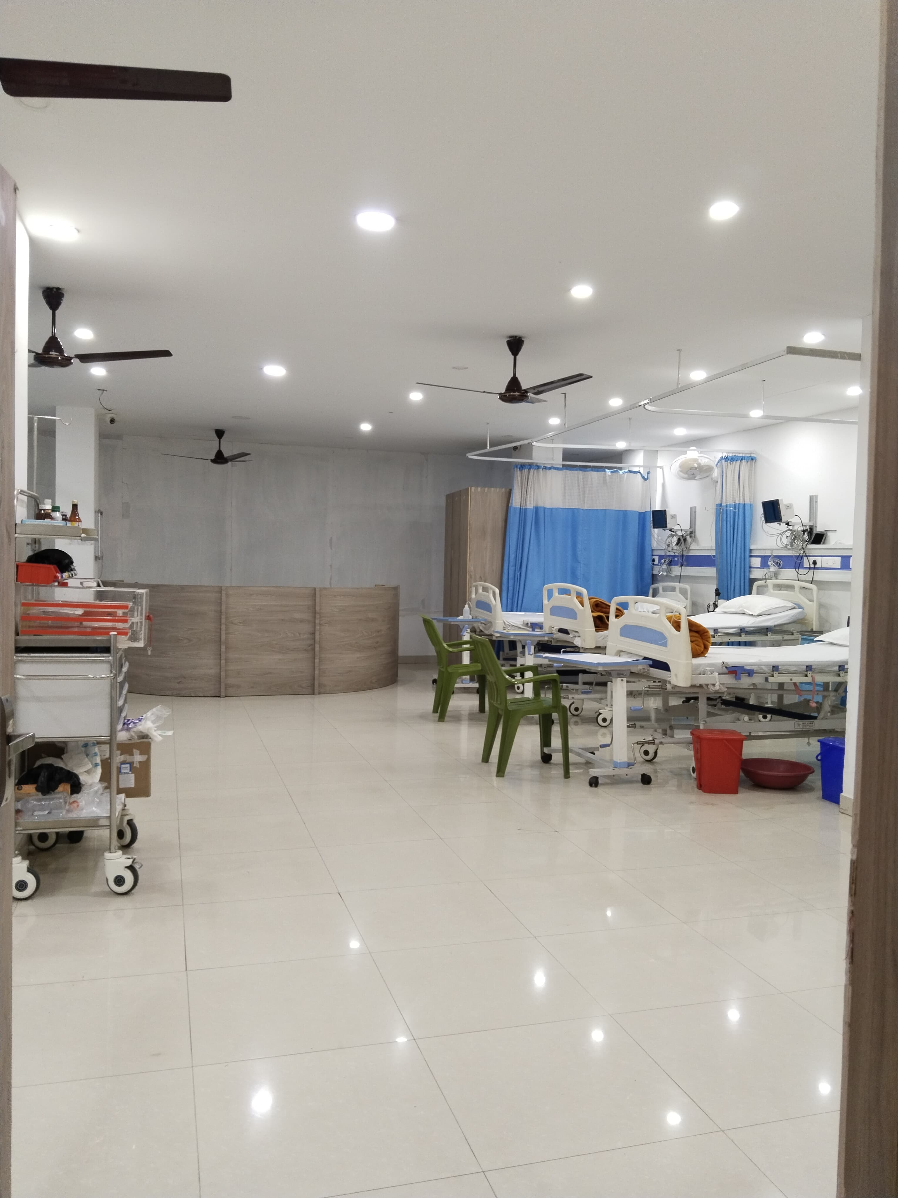 Spacious patient ward with multiple beds, privacy curtains, and monitoring equipment at Navya Hospital